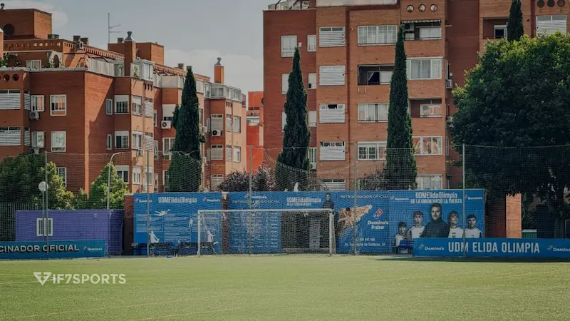 View of the UDM Elida Olimpia soccer field in Vallecas, Madrid, with nets and residential buildings in the background
