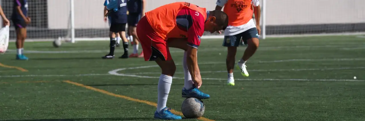 Player tying his shoelaces while stepping on the ball
